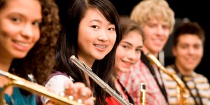 High-school girl playing flute with schoolmates