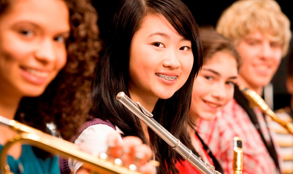 High-school girl playing flute with schoolmates